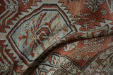 Distressed diamond medallion with serrated edge in pale blue and brick red tones.