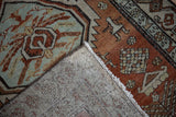 Distressed vintage Persian runner showing worn brick red pile, hand-knotted foundation, and fringe.