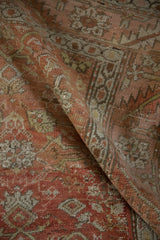 Close-up of antique distressed Bakshaish rug, highlighting worn texture, Herati motif, and muted colors.