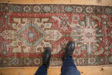 Distressed Heriz runner with geometric medallion design and faded cherry red, blue hues.