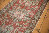 Distressed pile texture with varied cherry red and blue tones on the Heriz runner.