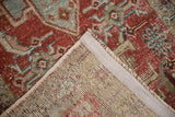 Hand-knotted Heriz rug corner with visible foundation, woven selvage, and distressed red, blue pile.