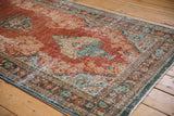Distressed brick red Mahal rug detail, showcasing ornate Rococo floral motifs and dusty teal accents.
