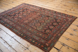 Vintage Kurdish rug upper corner displaying worn germinating plant motifs and madder root red vine borders.