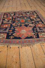 Vintage Caucasian rug corner with geometric finned animal motifs, purple border, and fringe.