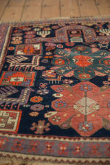 Geometric finned animal and pinwheel patterns in navy, red, and purple on a vintage Caucasian rug.