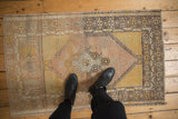 Distressed Oushak rug with mostly even wear, featuring pale pink, saffron, and silver tones.