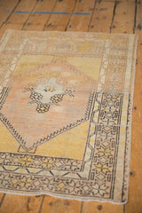 Distressed vintage Oushak rug showcasing worn knot heads, pale pink, and saffron yellow patterns.