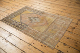 Vintage distressed Oushak rug corner with pale pink and saffron time-softened geometric border.