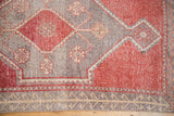 Oushak rug corner with geometric guls, plant border, and distressed pale red, silver pile.