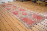 Distressed pale cherry red pile, foundation visible, with ivory plant border.