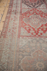 Angled view of the meandering vine border and red medallions on a distressed Anatolian runner.
