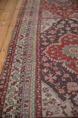Angled view of intricate geometric borders beside the charcoal field of a vintage Turkish runner.