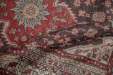 Folded vintage Anatolian rug showing its low pile and patterns in cherry red and dark charcoal.