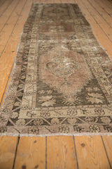 Distressed Oushak runner edge shows time-softened floral cross-section borders and fringe.