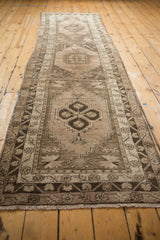 Fringed end of distressed Oushak runner, with silver and charcoal floral cross-section border.