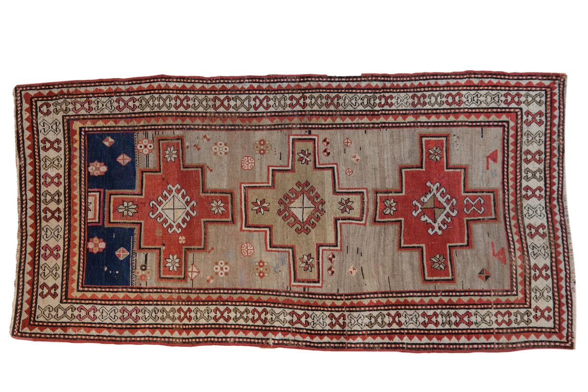 Vintage Caucasian runner with three stepped medallions in madder red and navy on a worn silver-beige field.