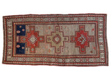 Vintage Caucasian runner with three stepped medallions in madder red and navy on a worn silver-beige field.