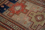 Low, hand-knotted pile of a vintage Caucasian rug with red stepped medallions and a geometric border.