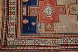 Close-up of the stepped red medallion and geometric crab-style border on a vintage Caucasian rug.