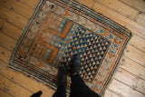 Feet on vintage Caucasian rug, showing geometric triangular motifs with rainbow-like abrashes.