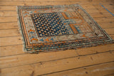 Vintage Caucasian rug corner, geometric border with tangerine, sky blue, beige motifs, and wear.