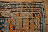 Vintage Caucasian rug corner with geometric triangular motifs in tangerine, beige, seafoam blue, abrashes, and wear.