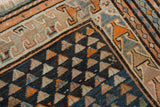 Vintage Caucasian rug corner: geometric border, navy field with inverted triangular plant motifs.