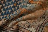 Geometric triangles and tangerine orange patterns with rich abrashes on vintage Caucasian rug.