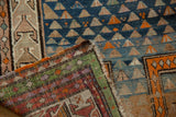 Vintage Caucasian rug close-up showing triangular motifs, distinct abrash, and colorful selvage.