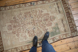 Distressed vintage Oushak rug with faded ivory, light brown, and pale green geometric-floral pattern.
