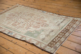 Distressed vintage Oushak rug corner with coffee brown border, ivory field, seafoam accents.