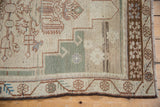 Vintage distressed Oushak rug corner: ivory field, sea foam green stepped pattern, brown floral border.