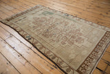 Distressed vintage Oushak rug, coffee brown border, faded floral vine motifs.