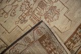 Distressed ivory Oushak rug corner, showing geometric pile, dark brown binding, and foundation weave.