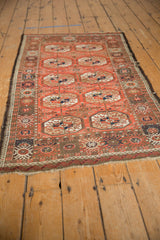 Afghani Bokhara design rug corner showing madder red gul motifs, textured pile, and dark goat hair selvage.