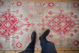 Evenly worn cherry red and ivory diamond patterns on a distressed Oushak runner.