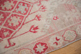Worn pile of distressed Oushak runner, highlighting cherry red floral motifs and faint ivory foundation.