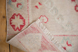 Detail of vintage distressed Oushak runner's folded corner, showing worn pile, fringe, and foundation.