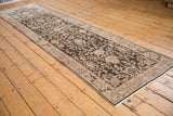 Full length of a distressed Sparta runner showing its charcoal sprawling vinery and floral pattern from an angle.
