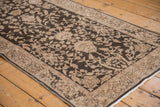 Distressed low pile of a vintage Sparta runner showing charcoal and beige floral arabesques.