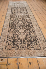 Lengthwise perspective of a distressed Sparta runner with charcoal and beige floral motifs.