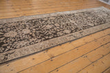 A long, angled view of the distressed Sparta runner's allover floral pattern in charcoal and ivory.