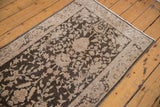 Angled view of the vintage runner's corner showing the distressed texture and beige floral border.
