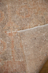 Distressed Oushak rug pile showing wear and its tightly woven beige reverse.