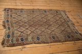 Antique Caucasian rug in pale camel, blue, rust tones, showing worn serrated panels and tattered ends.