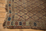 Antique Caucasian rug corner, tattered fringe, serpent border, and geometric patterns.