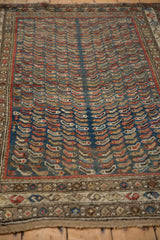 Angled view of vintage Caucasian rug featuring schools of fish motif and ornate boteh border.