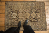 Vintage Caucasian rug corner: charcoal, ivory starbursts, arrowed leaves, and pawn motif border.