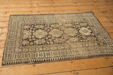 Vintage Caucasian rug's geometric border, highlighting charcoal and ivory pawn motif and edge wear.